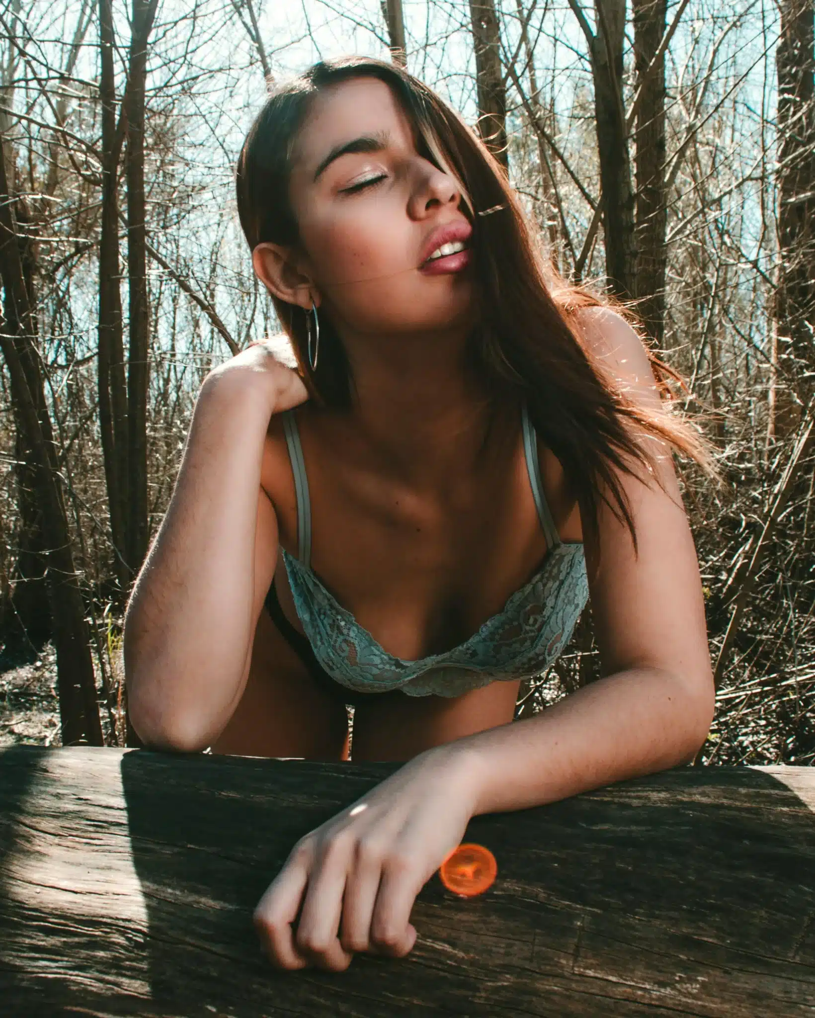 sexy woman posing outdoors near a log