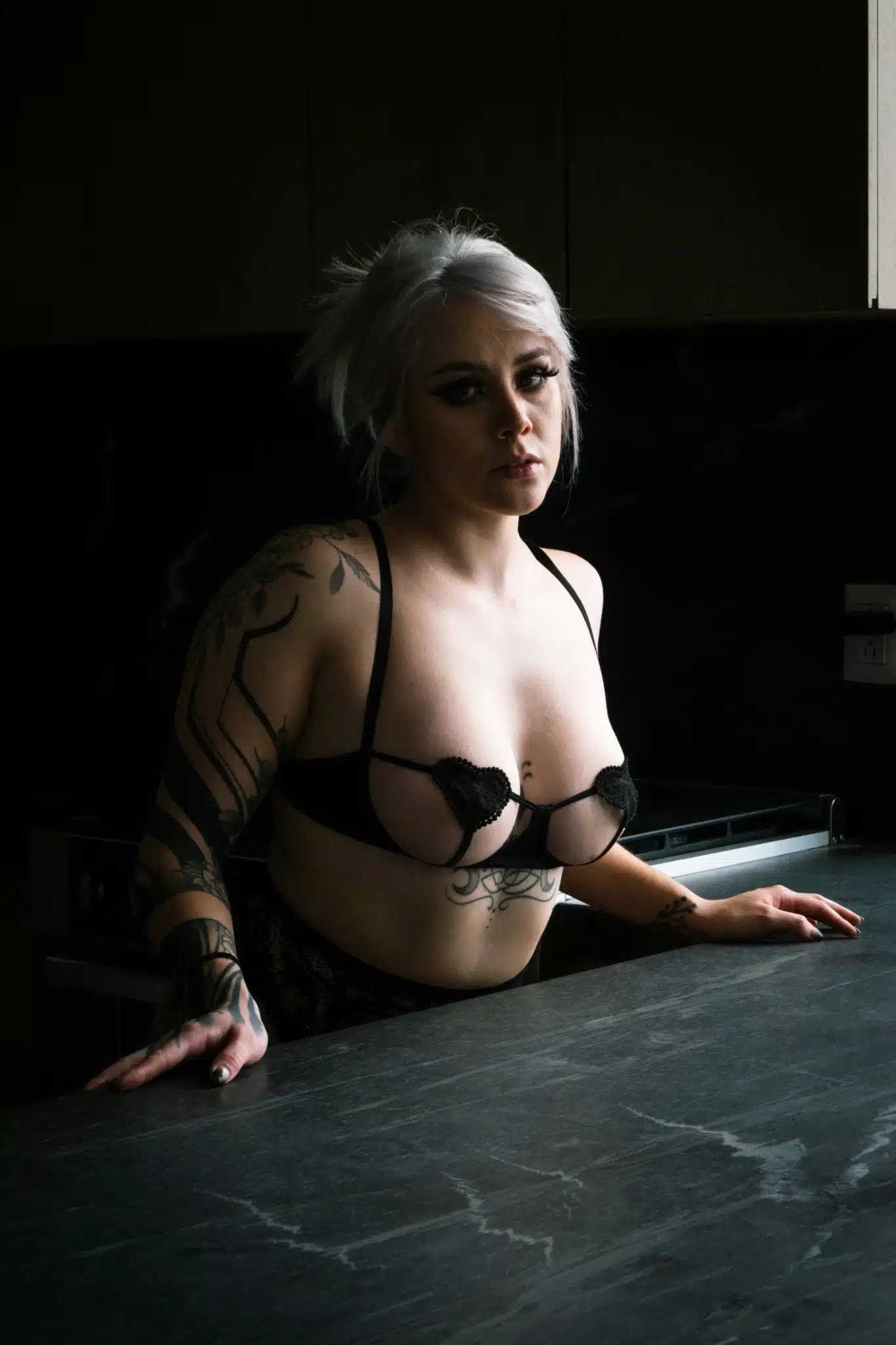 Tattooed person in lingerie at kitchen